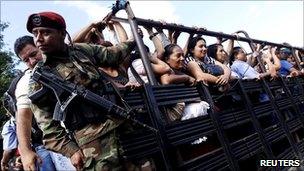 Soldier escorting commuters on a truck in San Salvador.