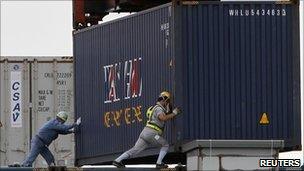 Workers load a container ship in the port of Tokyo