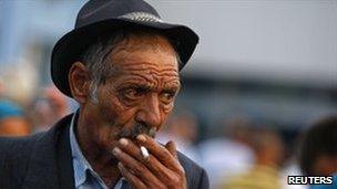 A deported Roma man smokes after arriving by air in Bucharest from Marseille, 14 September