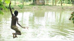 Boy jumping into pond