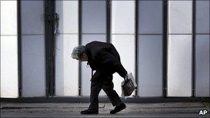 An elderly woman walks by a shrine in Tokyo