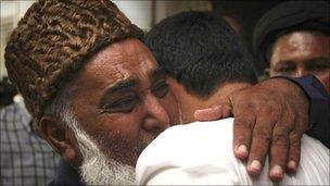 A man comforts a family member of Imran Farooq in Karachi