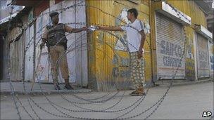 Paramilitary soldier checks the curfew pass of a civilian