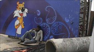 A man rests in front of a Games advertising hoarding in Delhi on Thursday