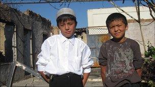 Shohruh (R) and Islam with Shohruh's charred house in the background
