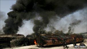 Police collect bullets shells next to burning oil tankers in Shikarpur, Sindh province, on 1 October 2010