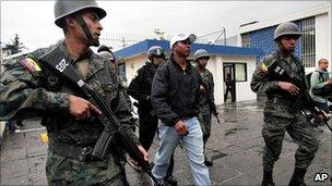 Soldiers escort a police officer arrested in connection with the revolt against President Correa