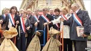 French mayors and members of the French Communist Party stand near trolleys carrying post bags full of petitions against the pension reforms that they are bringing to the Elysee Palace on 6 October 2010 in Paris