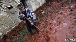 An elderly man tries to clean up his home in the flooded village of Devecser