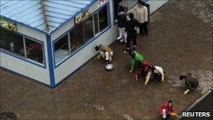 Women hand-wash a pavement in front of food stands in Pyongyang