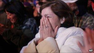 A woman reacts as she watches the televised rescue