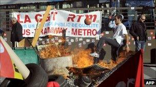 A bus driver in Marseille kicking a ball behind a fire at the entrance to the Capelette bus depot, blocked by CGT union members