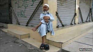 Shopkeeper Muhammad Hussain sits outside a closed market in Karachi on 17 September 2010