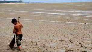 Boy plays with paddle on the dried up bed of the Negro river