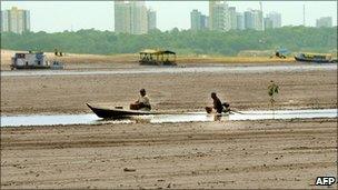 Two fishermen on a boat on the dried bed of the Negro river, 120km from Manaus