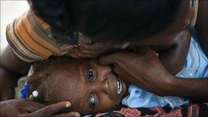 Child with cholera is comforted by a woman in hospital in Grand-Saline, Haiti, 23 October 2010