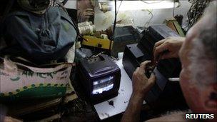 An electrician repairs a TV set in Havana