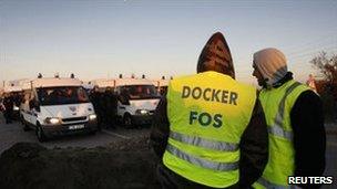 French dockers block the entrance of a fuel depot as police stand by in Fos-sur-Mer, near Marseille, 25 October