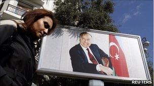 A woman passes a billboard of late President Haydar Aliyev