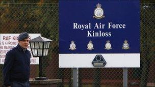 Royal Air Force personnel walk past a sign at the entrance to the RAF Kinloss airbase in Moray