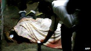 A man places a candle next to a dead body in Tepito, Mexico City