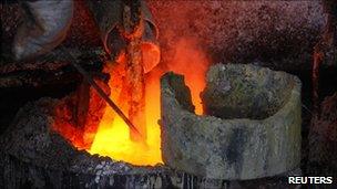 A worker at Jinyuan Company's smelting workshop, stokes the pots containing the rare earth metal Lanthanum, near Damao, in China's Inner Mongolia Autonomous Region, 31 October