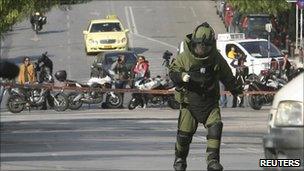 A police explosives expert arrives to detonate a suspicious package (1 Nov 2010)