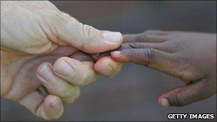 White adult hand and black child's hand