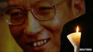 A protester holds a candle next to a portrait of Liu Xiaobo
