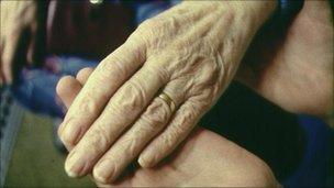 Elderley patient and helper hold hands