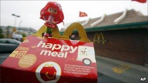 A toy sitting atop a fast-food meal outside a McDonald's restaurant