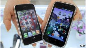 A shopkeeper in South Korea holds the Galaxy S from Samsung (right) and Apple's iPhone 3G