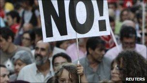 A child holds a banner as people take part in a protest held by unions