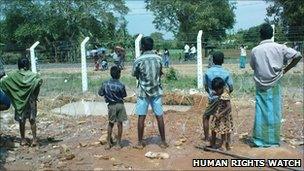 Internally displaced people, including children, in one of the internment camps in Vavuniya try to communicate with their relatives through double rolls of barbed wire.