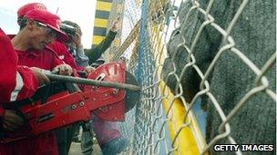 Policemen cut the fence of a Swiss-owned factory in Vinto, Bolivia, in February 2007 after President Evo Morales nationalises the company