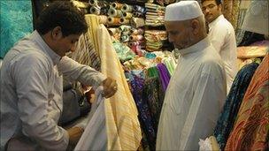 A man shows fabric to another man in a market in Mecca