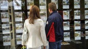 Two people looking in an estate agent's window