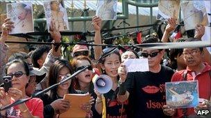 Red shirts wave pictures of people killed when troops quashed protests six months ago, outside Bangkok's Remand prison 19 Nov 2010