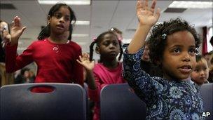 Yasmin Long, 8, left, from St. Lucia, Jessika Lionel, 6, from Haiti, and Mirette Franklin, 4, from Ethiopia, all adopted children, repeat the pledge of allegiance, 18 November 2010, in New York