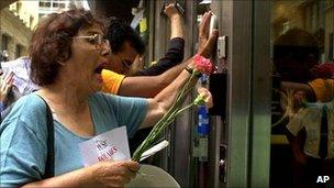 Demonstrators bang on the door of a bank in the financial district of Buenos Aires, February 2002