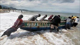 Fishermen pushing their boat out to sea in Sierra Leone