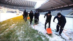 Staff clear snow from the pitch at St James' Park in Newcastle