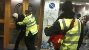 A police officer tackles a protester inside Lewisham town hall