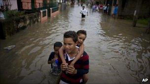 A boy carries a girl on his back through the flooded streets of Higuerote, Venezuela