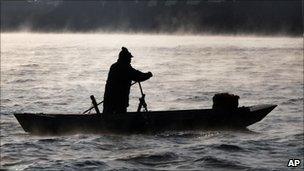 A Chinese man rolls a boat on the Yalu River, the China-North Korea border river