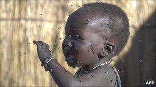 A child with flies buzzing round its face