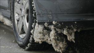 Snow clings to the underside of a car