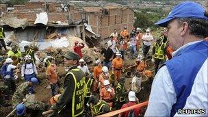 President Juan Manuel Santos looks on as rescuers dig for landslide victims