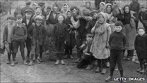 Children, wearing clogs, gather coal in 1921