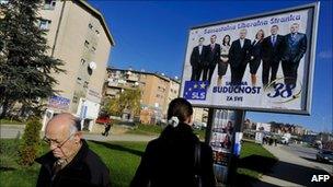 Kosovo Albanians walk past an election advertisement in Pristina (8 Dec 2010)